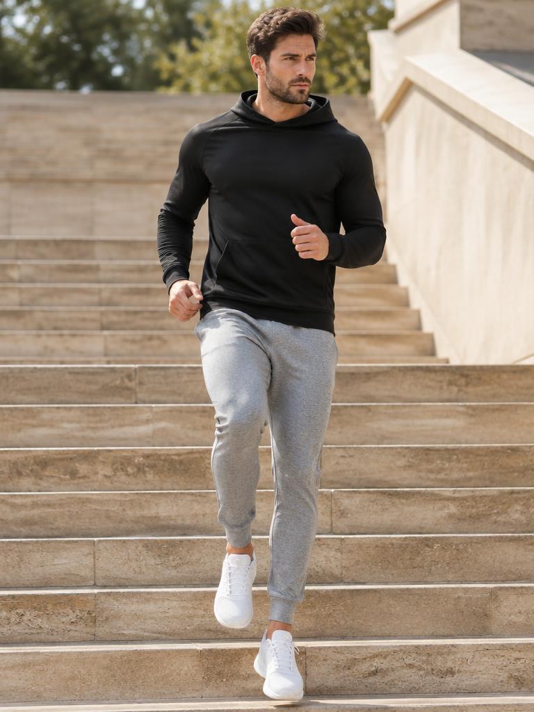 Man running down stone stairs in black hoodie and grey joggers