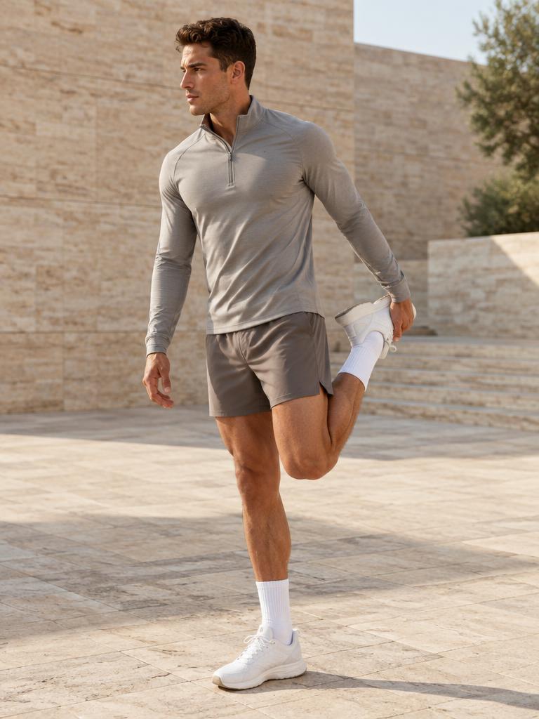 Man stretching in grey quarter-zip and taupe shorts